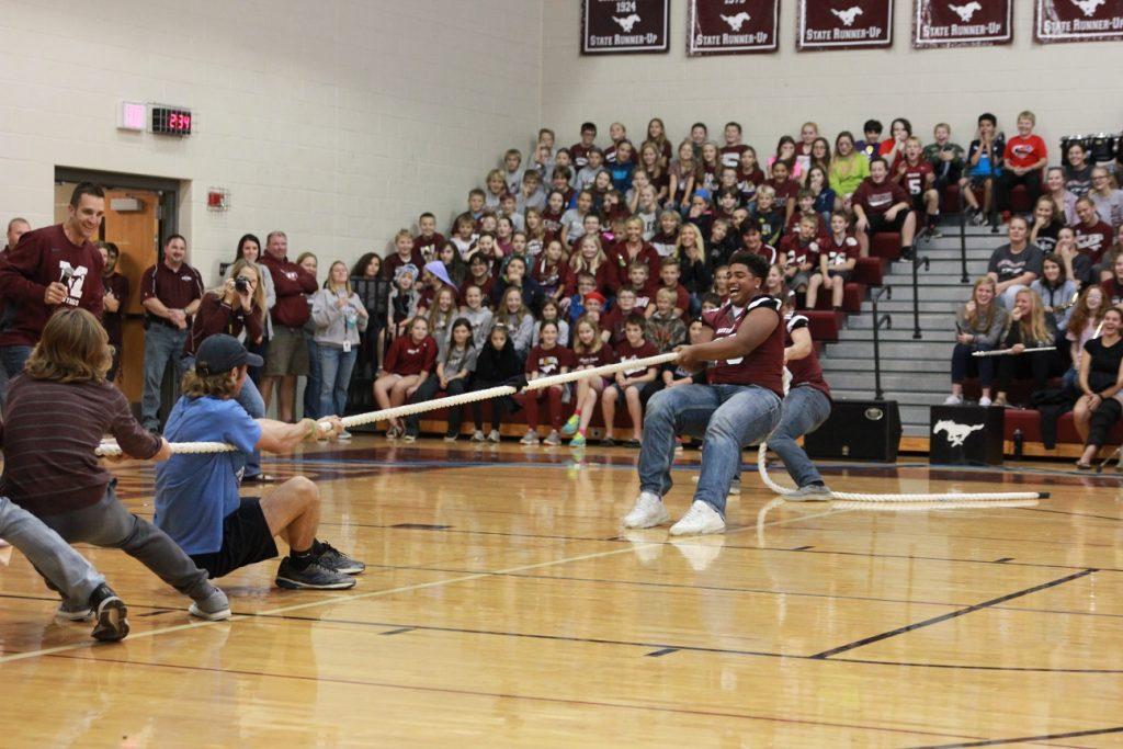 Senior Tristan Wirfs helps the football team win the first round of tug-of-war against the boys cross country team at the homecoming pep rally on Sept. 30. Photo by: Summer Everhart