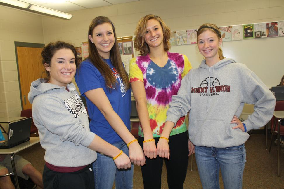 Micah Wieditz, Taylor Dicus, Courtney Kintzel, and Jenna Pisarik pose with their bracelets that honor Coach Stamp.  Micah and Jenna are on the softball team, and all team members are selling the bracelets for $2 each.