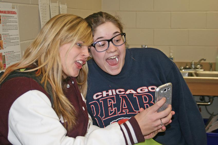 Junior Miranda Chapman and sophomore Abbey Teubel pose as Miranda snaps a picture on Snapchat.  Students use the app to send photos to friends that can only be seen for up to 10 seconds. Photo by Hannah Wieditz.