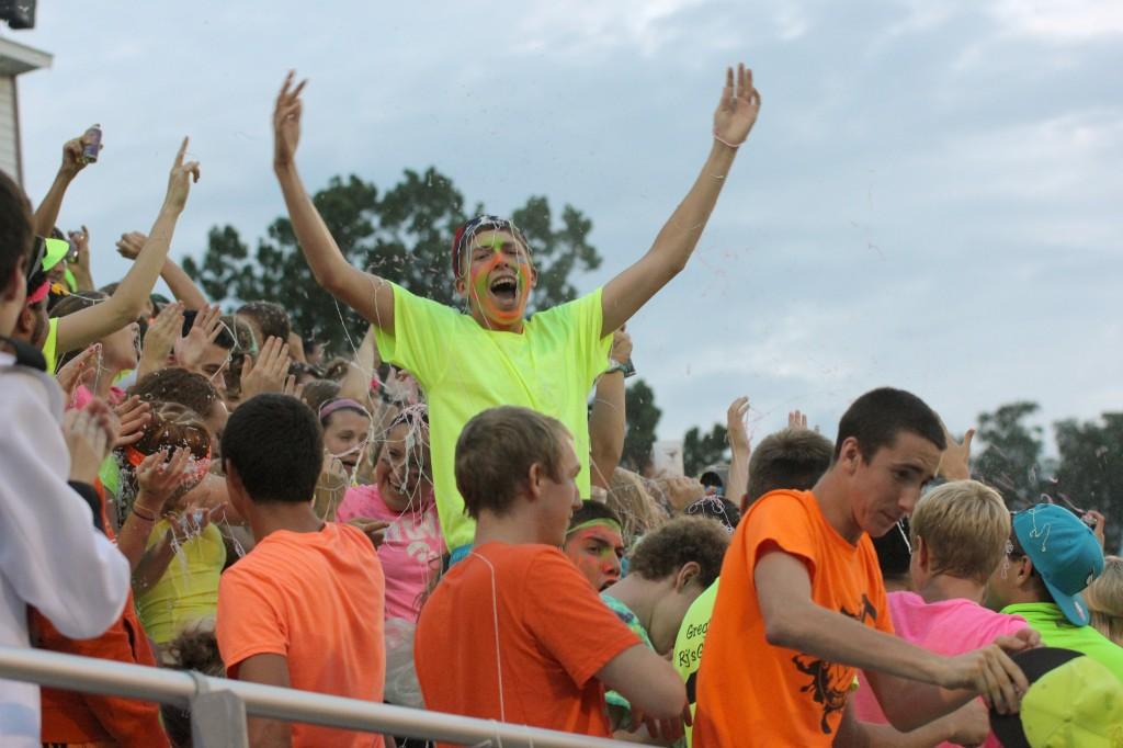 Junior Ben Alger cheers for a touchdown in the neon crowd among the spray of silly string. Photo by Lexi Kelly.