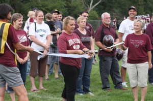 Joy Kuntz cuts the ribbon to dedicate the field before the game begins. Photo by Lexi Kelly.