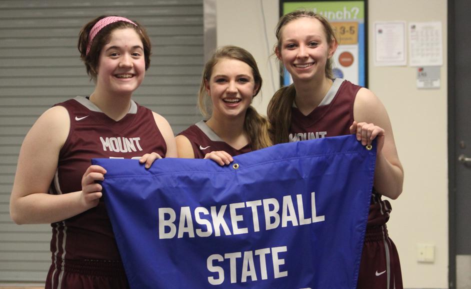 Abbey Teubel, Lexy Kroeger, and Alli Platte hold the state qulaifier banner after their 55-48 win over CPU Feb. 21.