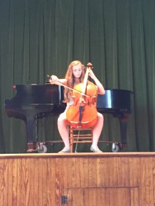 Clara Conroy plays cello on stage. 