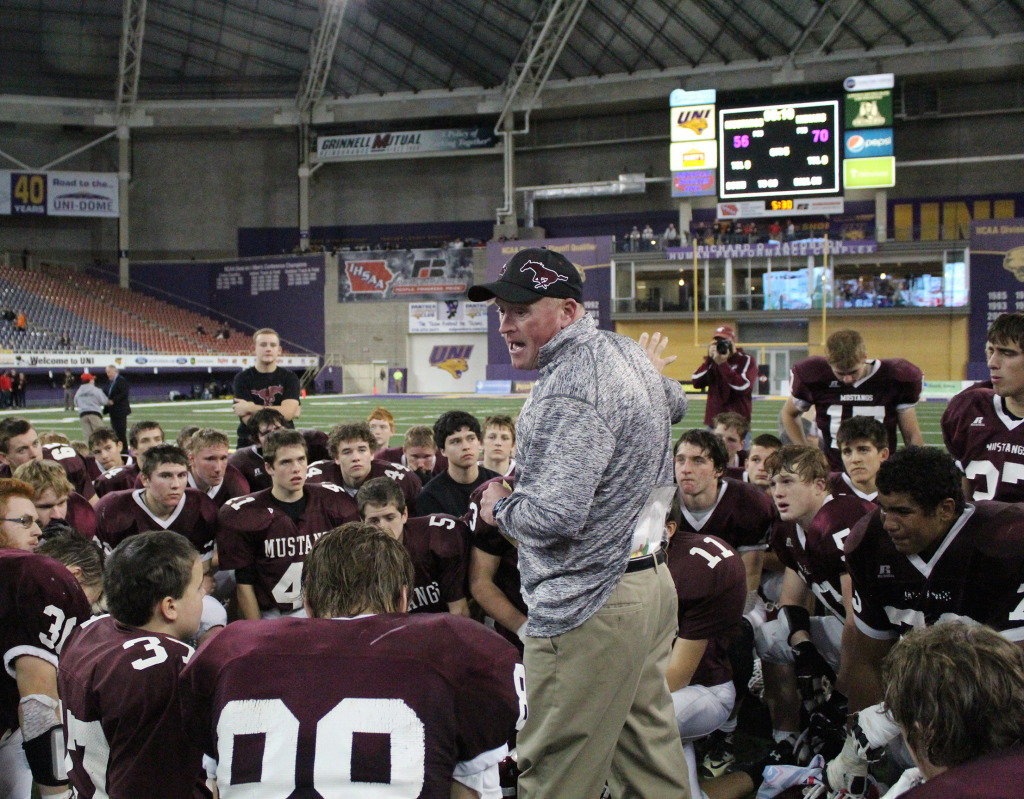Head Coach Lance Pedersen talks to the team after the record-breaking state championship game Nov. 23. The photo tells the story of the hard fight with the high-scoring loss recorded on the scoreboard: Mount Vernon 56, Spirit Lake 70. Photo by Bailey Priborsky.