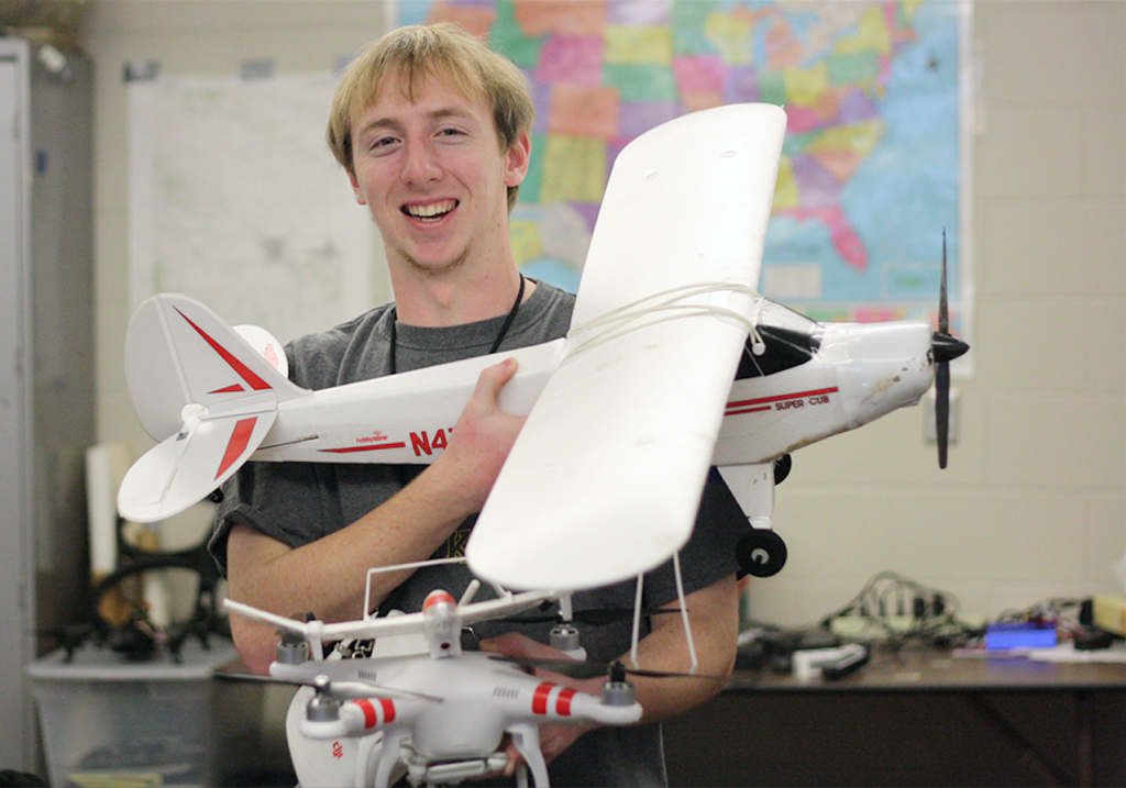 Jordan Axtell poses with a model airplane and a drone in science teacher Richard Scearce's class Jan. 7. Photo/ Mason Stanbro. 