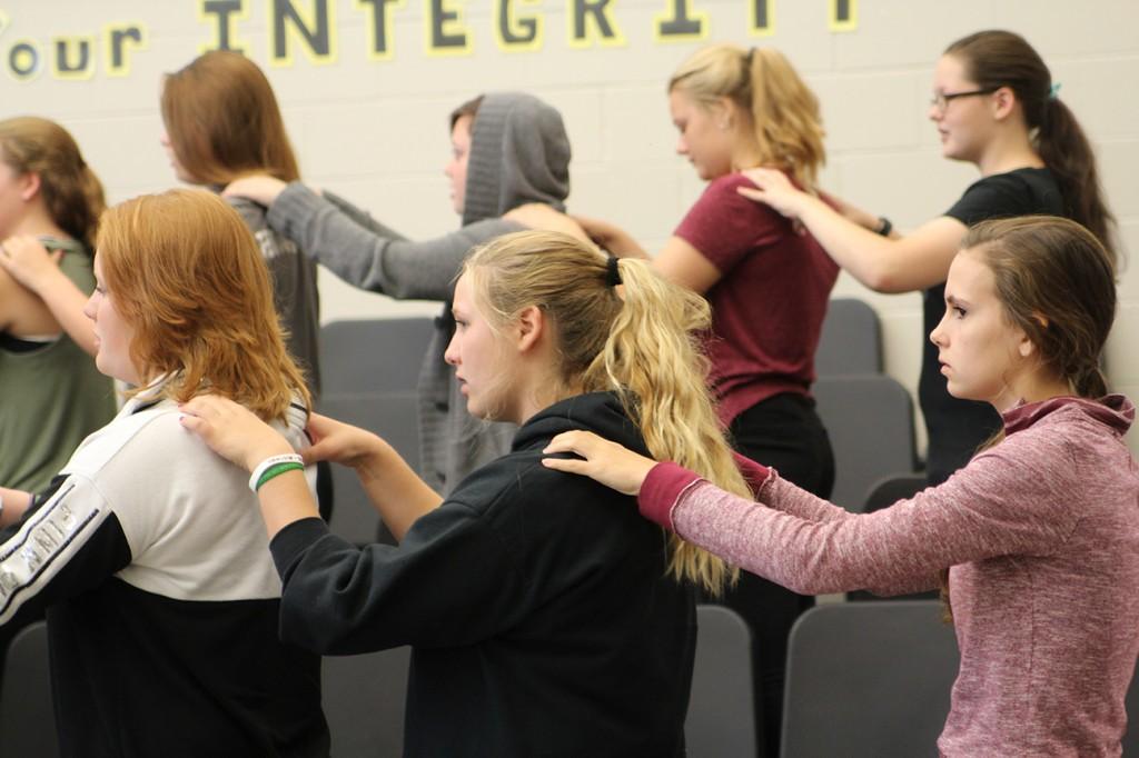 Members of the ninth and tenth grade women's choir warm up before class with massages. Photo by Lauren Hauser.