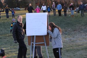 High school parent John Gruber-Miller and sophomore Sam White write messages in the middle of the circle.