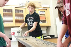 Freshmen Derek Jordan, Sean Christmas, and Reilly Gross pour water onto their model stream Nov. 1. Photo by Brian Harris.