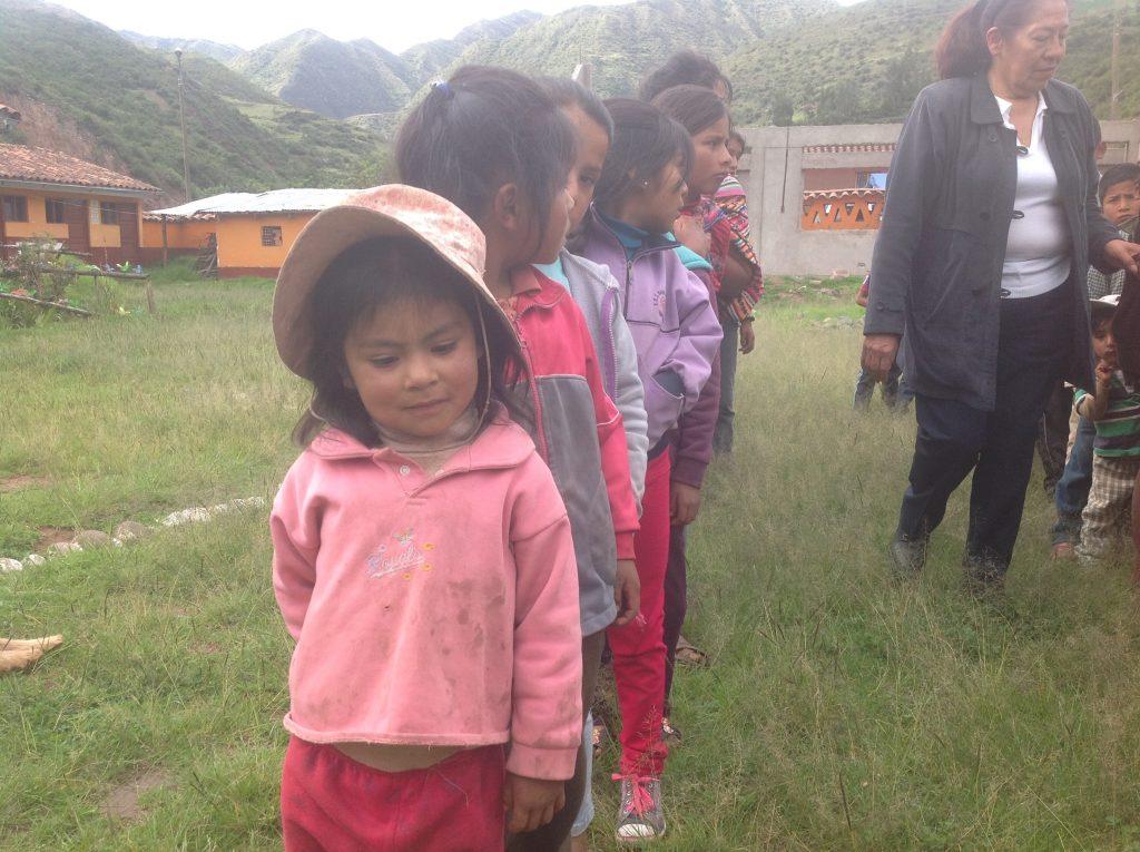 A little girl from Peru waits to play a game with students from Iowa. Before this picture was taken, the little children that go to school in Peru got bags of school supplies. Photo by Sue Deibner.
