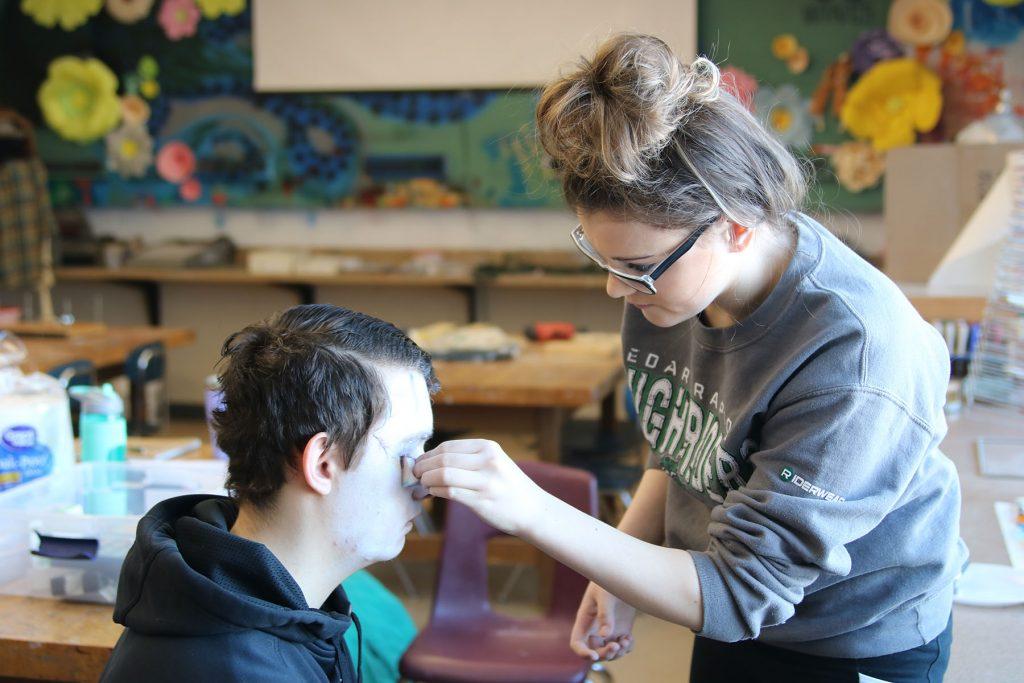 Abby Davidson, a junior, paints the face of Phillip Hyde, a sophomore. Photo by Caroline Voss.