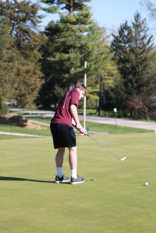 Sophomore Collin Swantz stands on the green and putts the ball in a meet against West Delaware. 