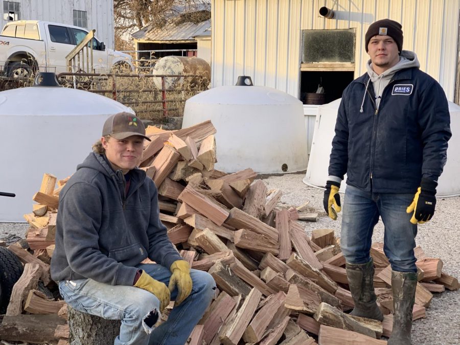 Trevor Ellison, junior, and Max Shady, senior, pose next to a pile of wood they  just cut.