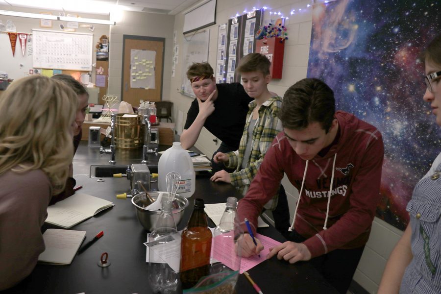 Sophomore Kian Hageman, junior Kaylynn Burgin, and senior Aubrey Frey observesophomore Jacob Russell take notes in their J-Term class, Herbology and Potions.