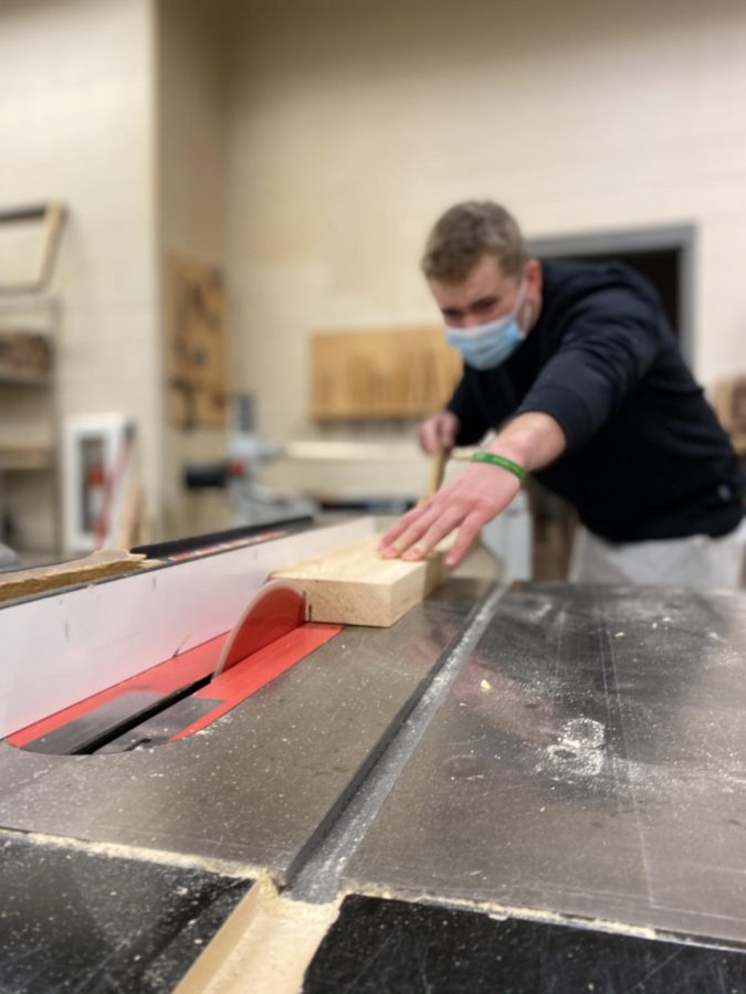Senior, Connor Klinkhammer, is slicing his other board using the table saw without a guard.