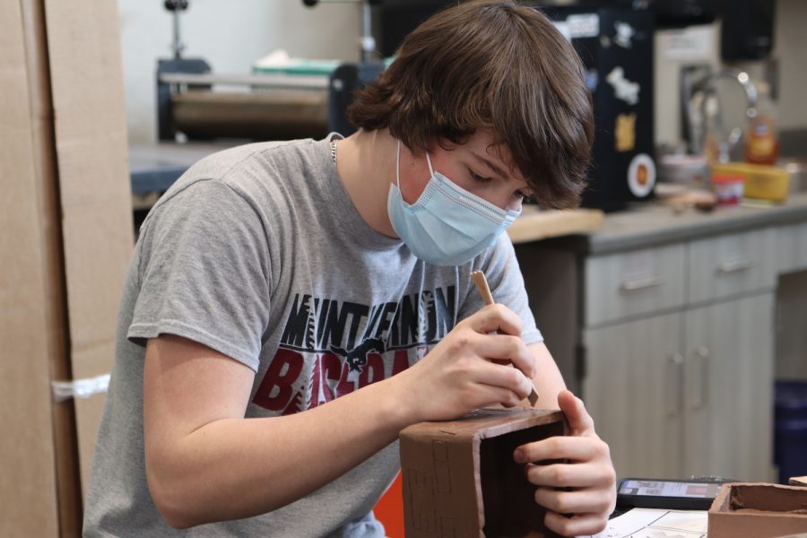 Clayton Flack, a sophomore, etches a design into his project in Ceramics Feb. 3. Flack planned out his designs based on Minecraft, each face depicting a different aspect of the game.