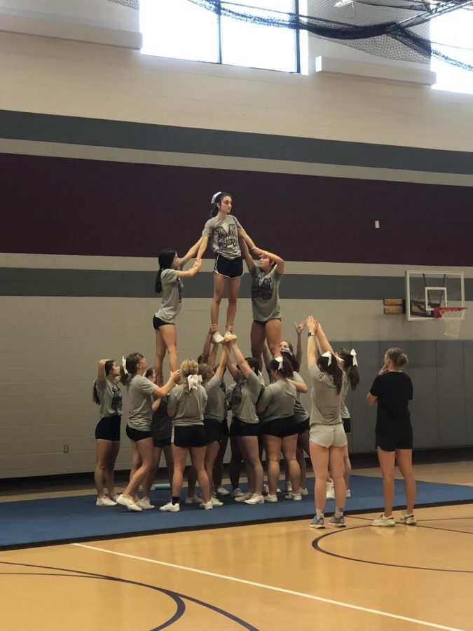 Flyer, Kambree Hultquist, practices a pyramid with the help of multiple teammates Aug. 28.