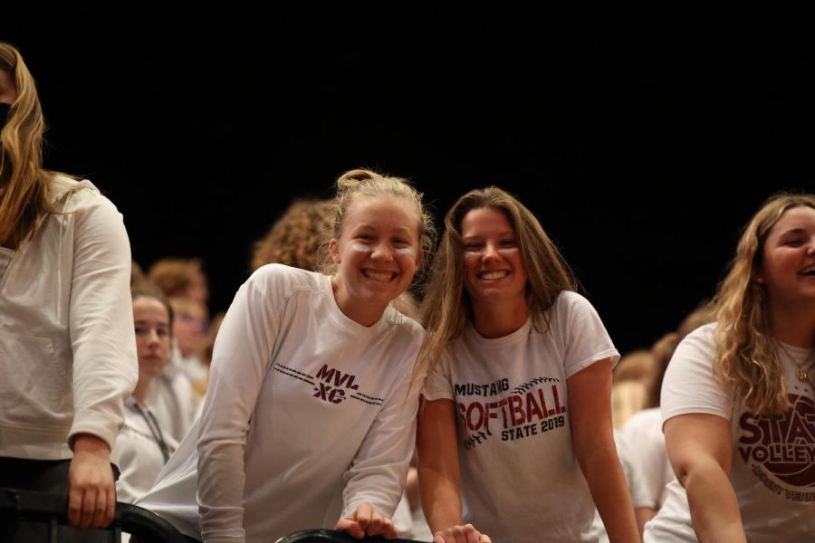 Seniors Kasia Wiebel and Jenna Sprague smile for the camera while cheering in the student section. 