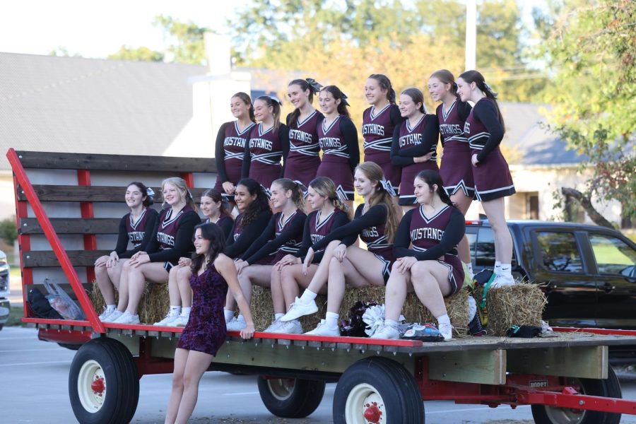 Cheerleading team poses with senior Ava Dimmer on their float before the parade.