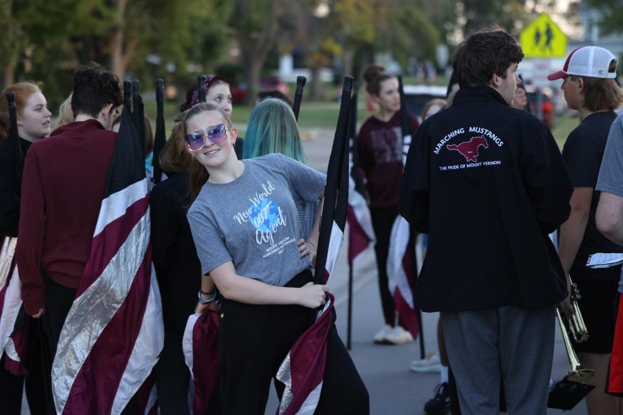 Sophomore Violet Olinger poses for the camera with her flag in front of the band.
