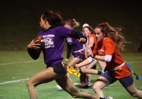 Senior Claire Gaffney lunges forward to stop freshman ball carrier Cali Whitaker on Sept 22 at the powderpuff football game. Whitaker sprinted past Gaffney and made it to the end zone to score a touchdown.
