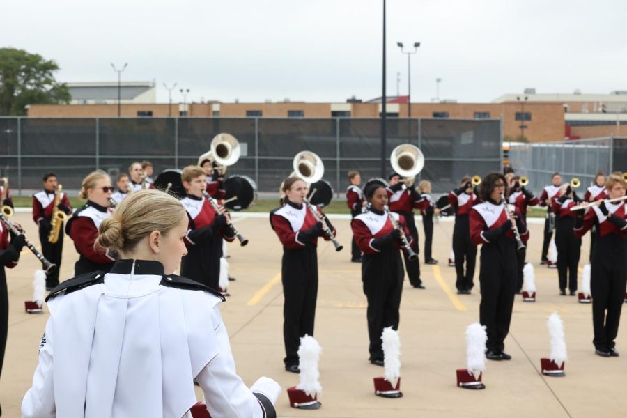 Junior Mollie Snedden conducts the marching band in rehearsal Sept. 24 before they take the field at Linn Mar. 