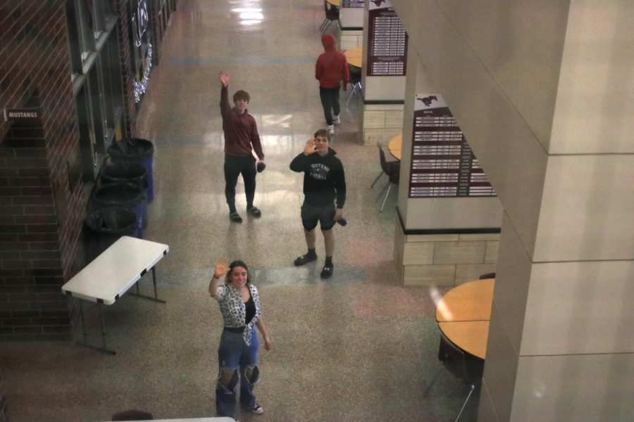 Sophmores Renee Vig, Collin Bently, and Kael Riniker stand in the middle of the entry of the school, waving at the camera during break. 