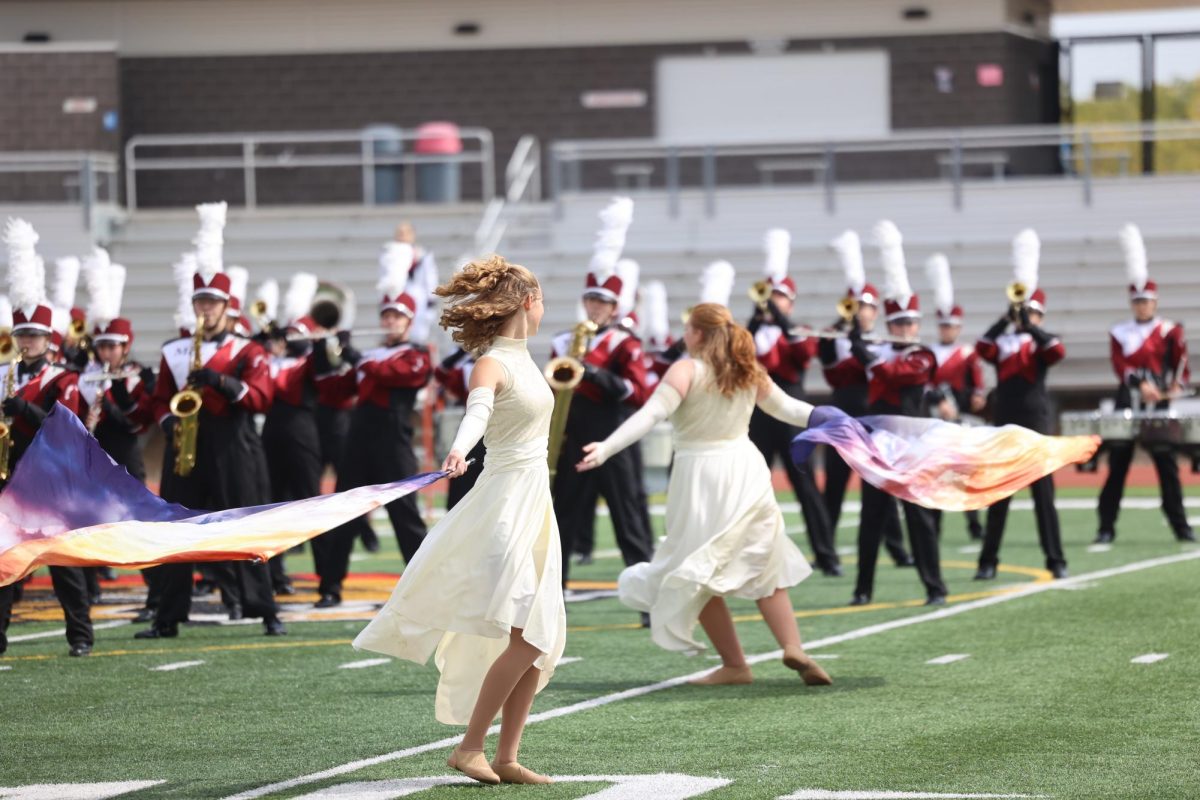 Freshman Eleanor Dye and Senior Sarah Fluharty twirl together in front of the marching band.  