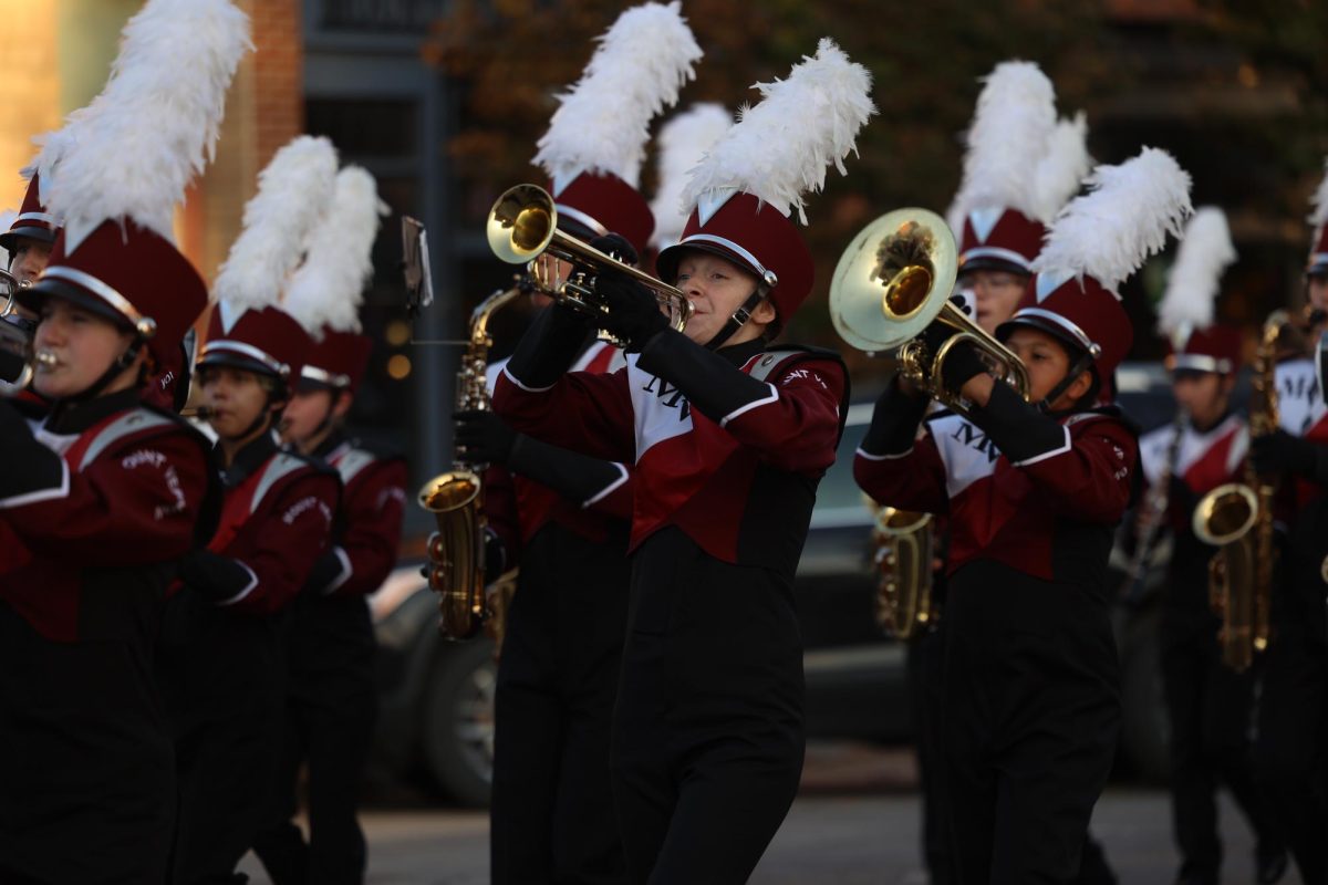 Sophomore Eva Bishop plays the trumpet while marching through the homecoming parade. 