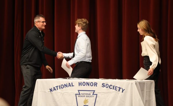 Principal Steve Brand shakes junior Colin Bentleys hand as he is inducted into National Honor Society Nov. 20 in the Performing Arts Center.