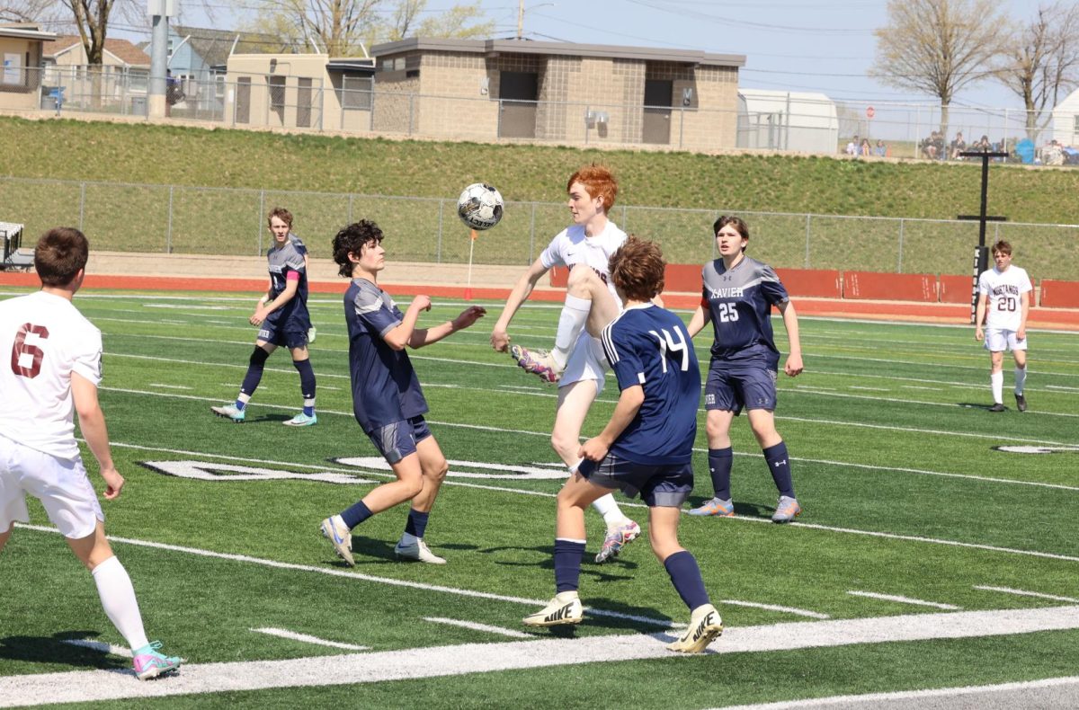 Senior Aiden Campbell (24) kicks the ball up and away from multiple Xavier defenders including Will Dybvig (14) on April 13th. 