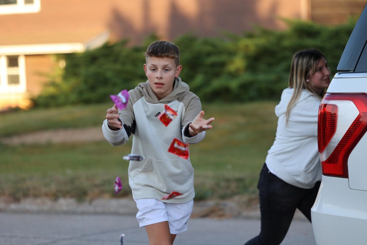 Sophomore Collin Boehler throws candy at a group of kids in the crowd of the Hoco parade. 