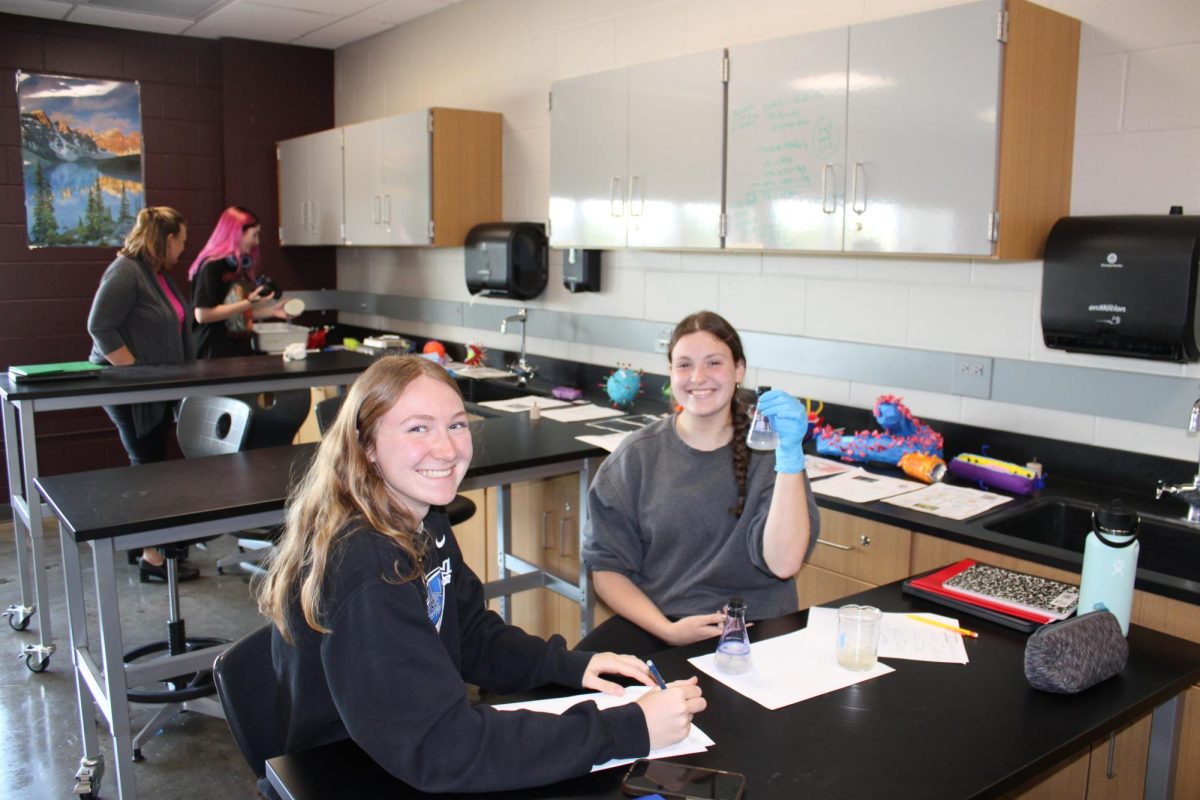 Sophomores Emily Bock and Alaina Pospisil smile at the camera, happy to show off their Honors Biology lab on Sept. 9.