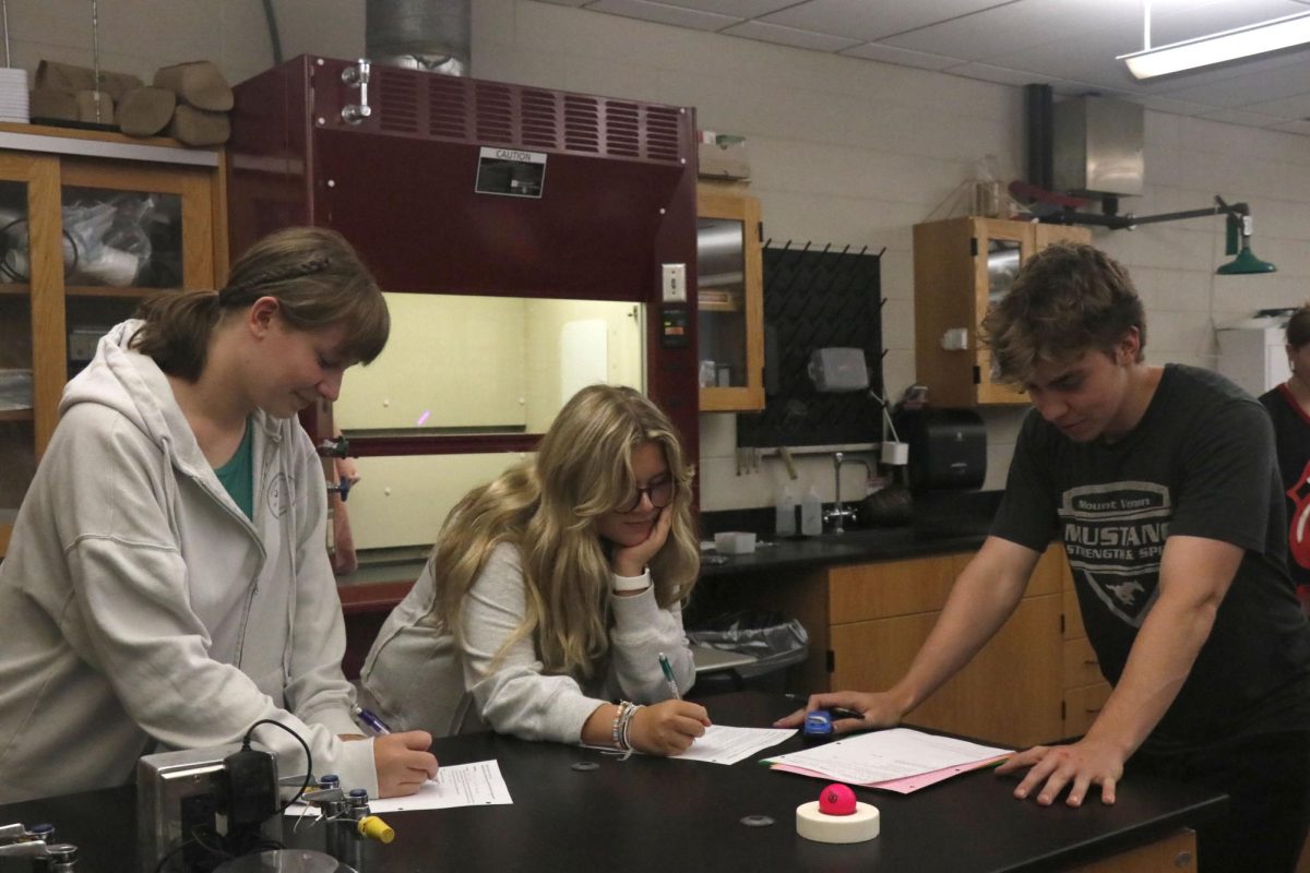 Juniors Katie Whitehead, Norah Weber, and Kevin Zehms write down data from their motion experiment in Physics on Aug. 28. 