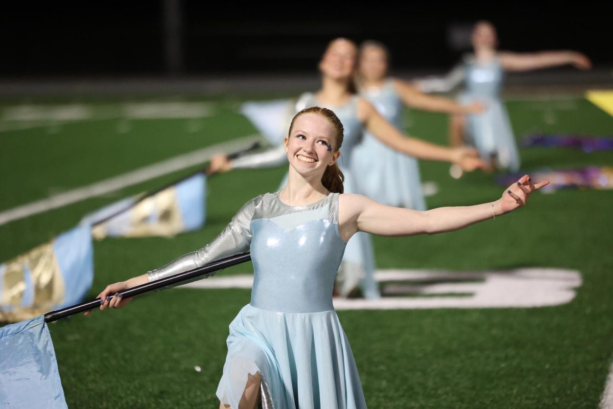 Junior Ingrid Morf smiles as the color guard gracefully performs alongside the marching band.