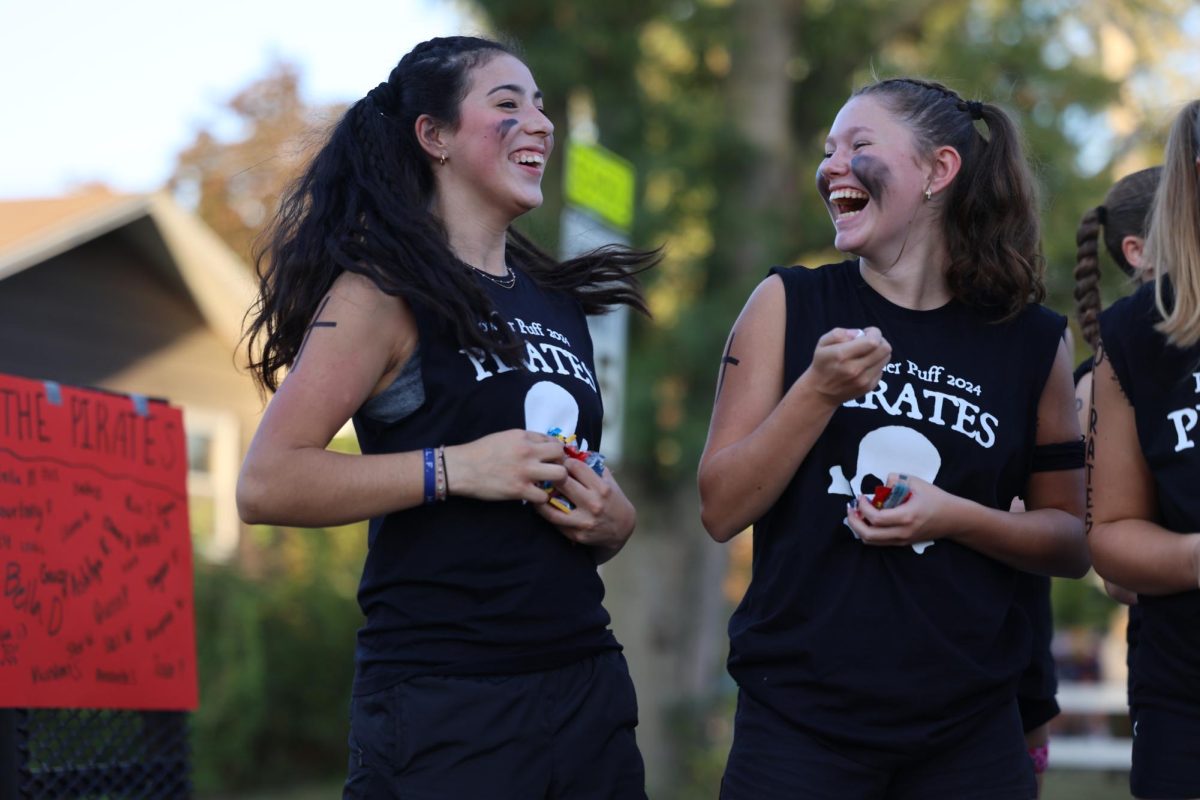 Juniors Bella Donatti and Kaia Swaim laugh while throwing candy at the crowd during the MV Hoco Parade. 