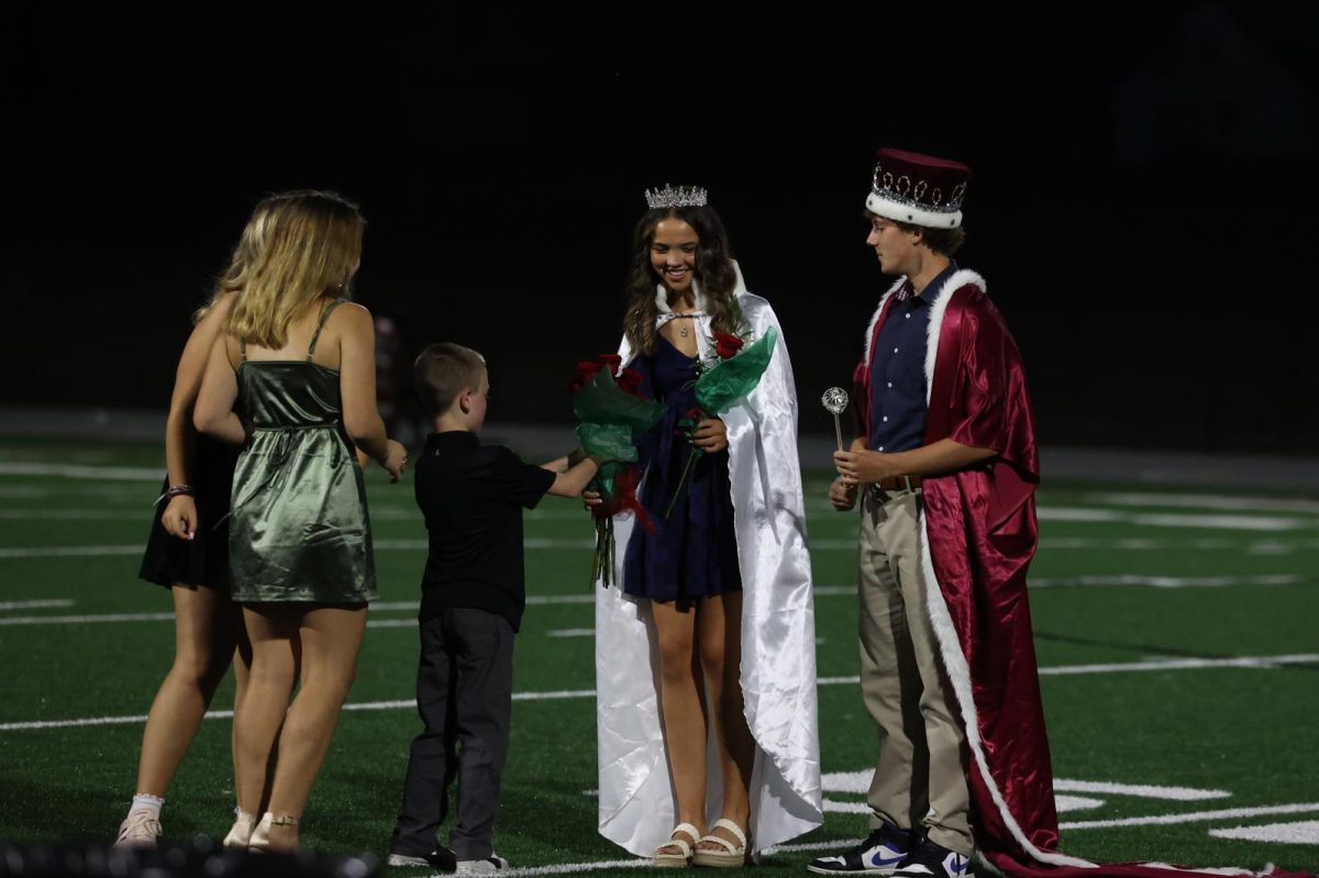 Homecoming Queen Betsy Louwagie and  King Seamus O'Connor smile while receiving flowers Sept. 26.