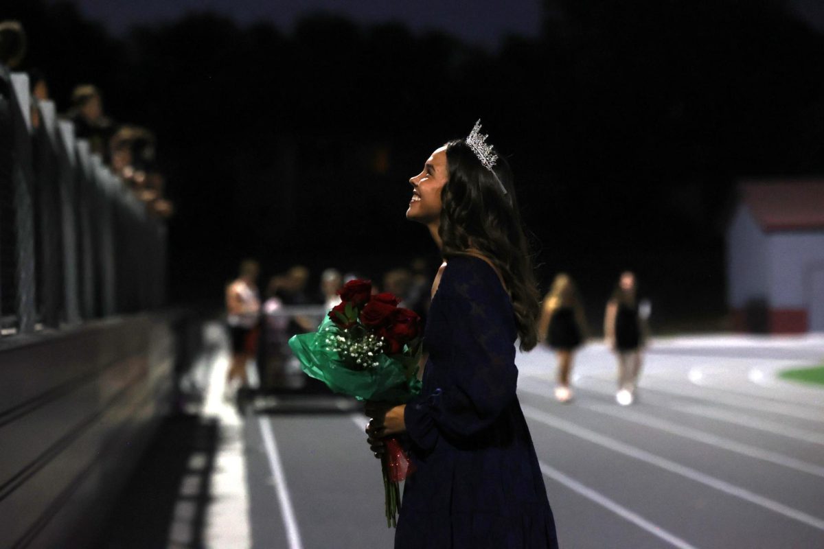 Homecoming Queen Betsy Louwagie smiles up into the crowd Sept. 26.