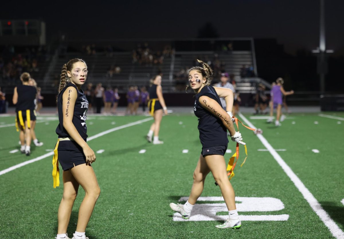 Freshman Savanna Wright listens back while junior Adeline Whisner puts on her flag Sept. 26.