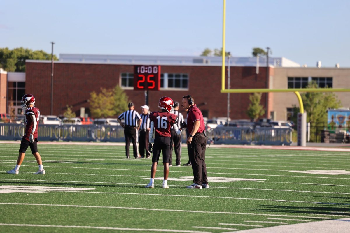 Freshman Teddy Bonewald (16) meets with his coach before a play.