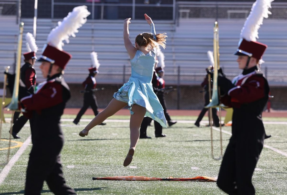 Senior Natalie Thuerauf leaps in the air as the Marching Mustangs begin their show at the Linn Mar competition on Sept. 28.