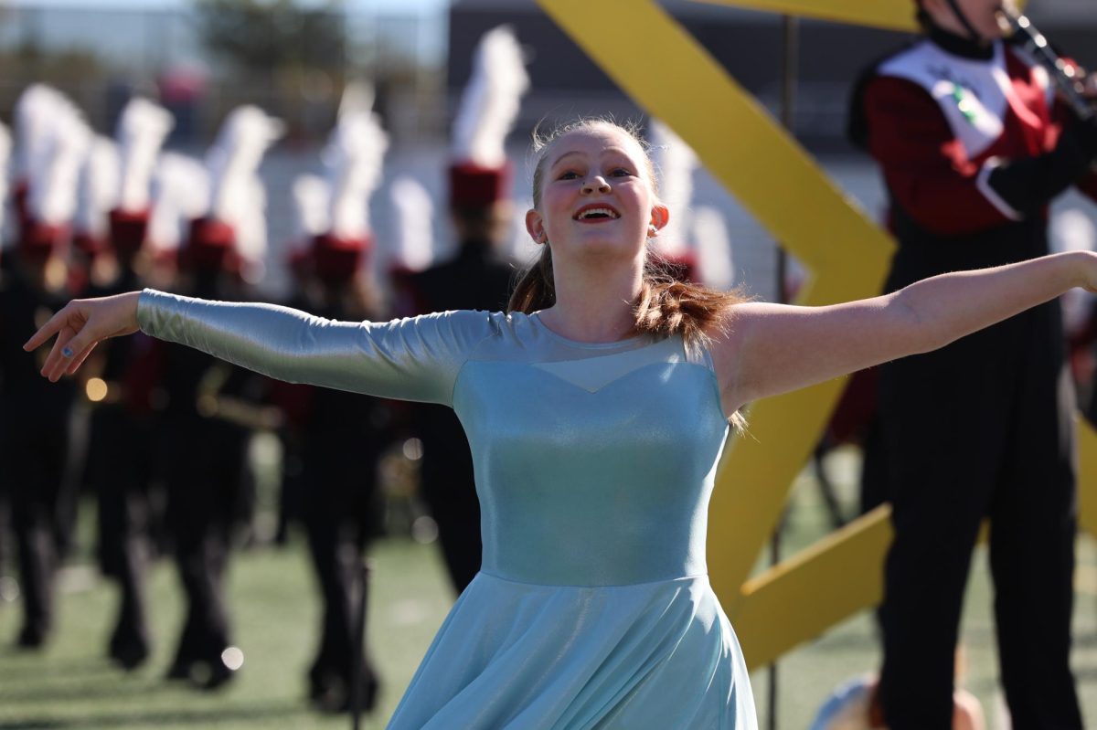 Senior Violet Olinger lands a pose during her color guard solo at the Linn Mar marching band competition.