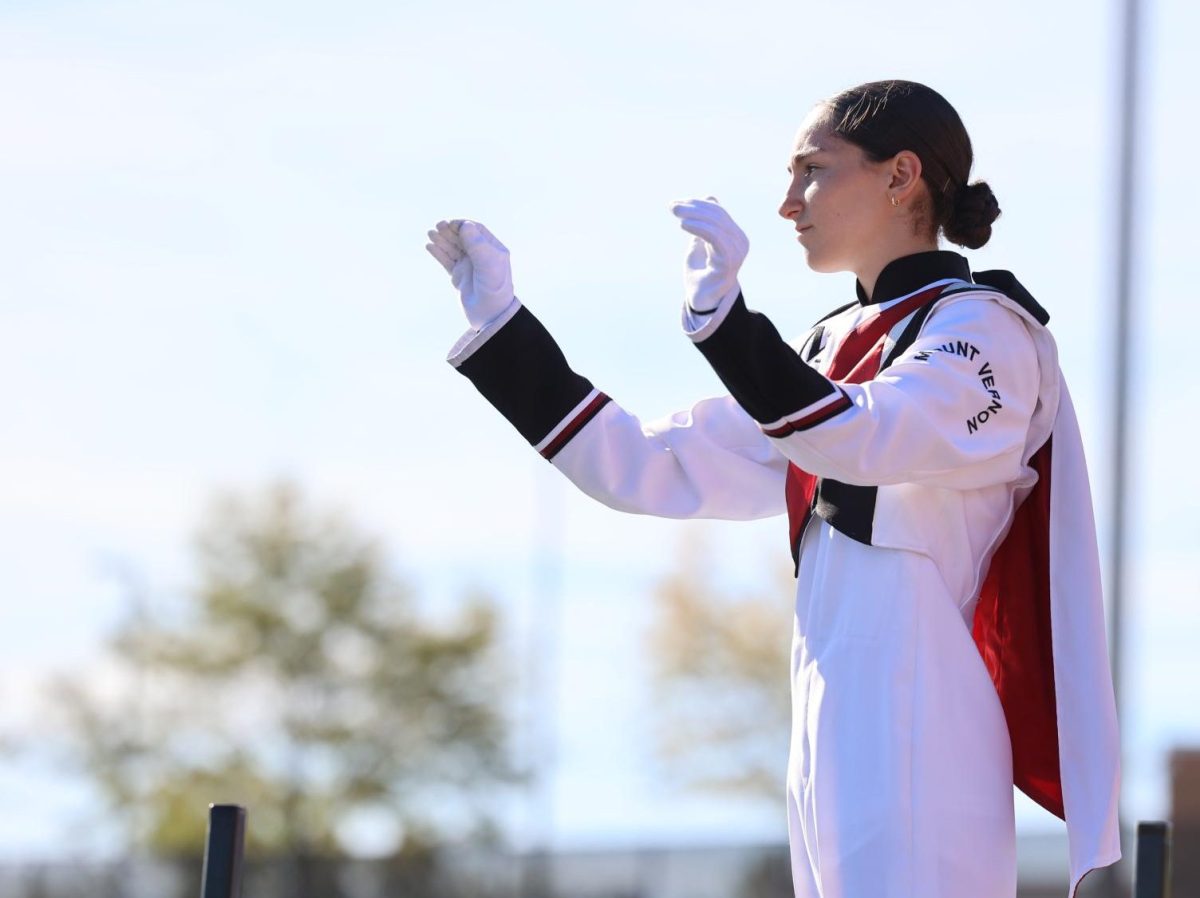 Sophomore Anna Stephens attentively conducts the marching band during their performance on Sept. 28.