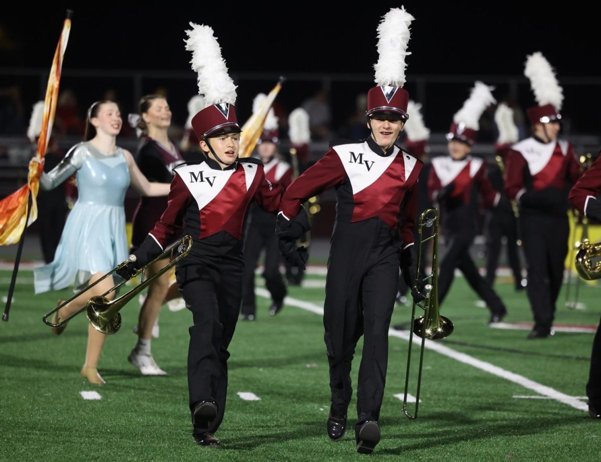 Freshmen Chris Schneider and Beck Oesterle skip around the field together at the start of the marching band performance on Oct. 11.