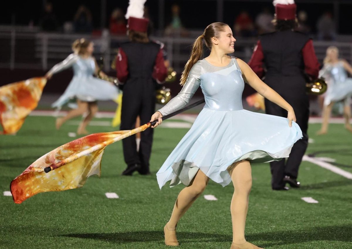 Senior Renee Vig gracefully performs with the color guard during the marching band halftime show on Oct. 11. 