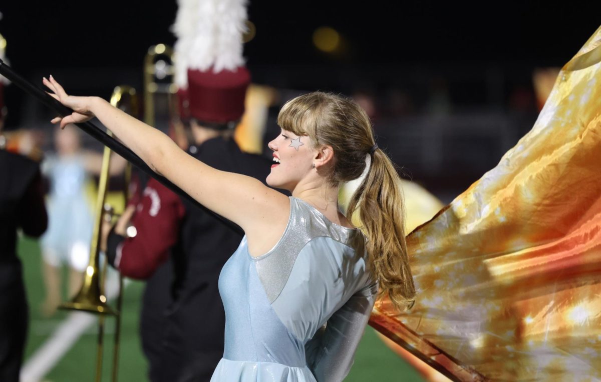 Senior Meg Dye waves her flag during the marching band halftime show. 