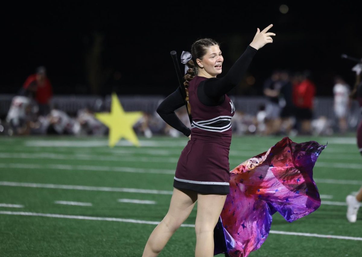 Senior Emma Houghtaling reaches for the stars at the end of the marching band halftime performance on Oct. 11. 