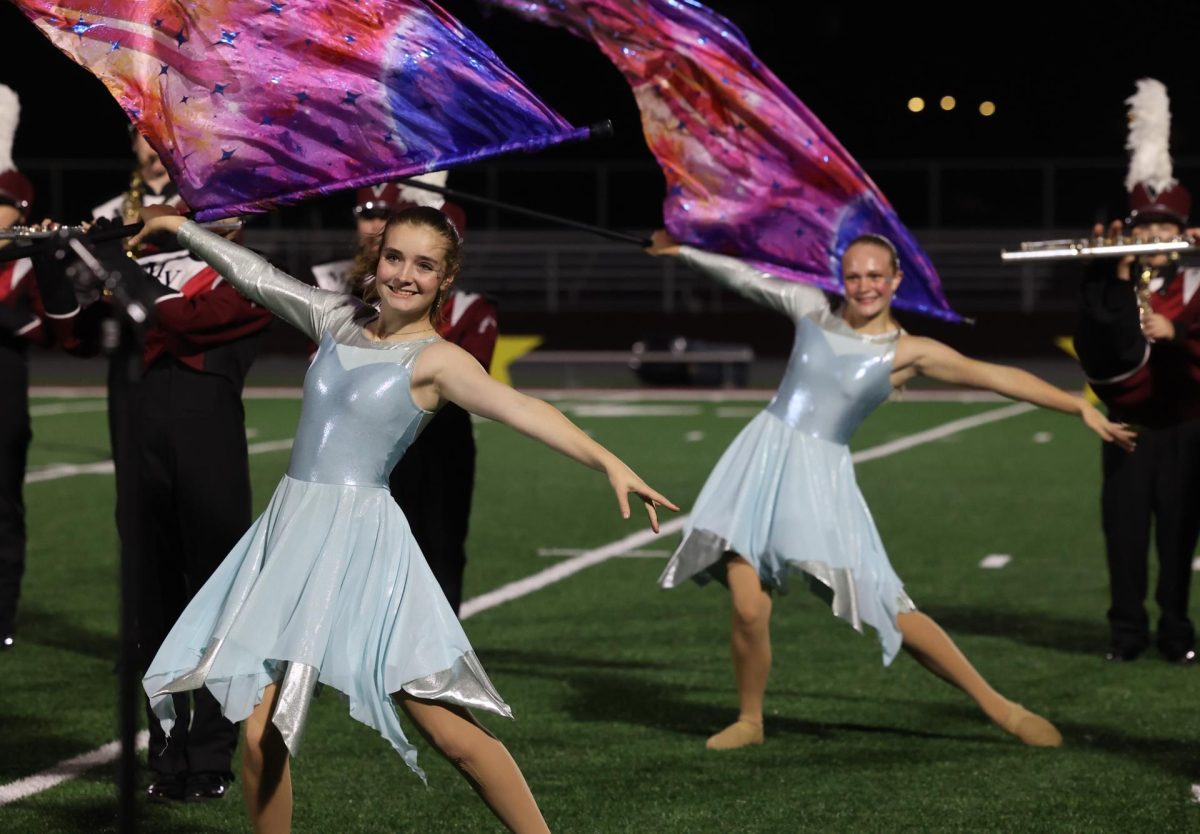 Senior Brandy Hills and Freshman Adrienne Ruhland wave their flags with the color guard during the band's final show. 