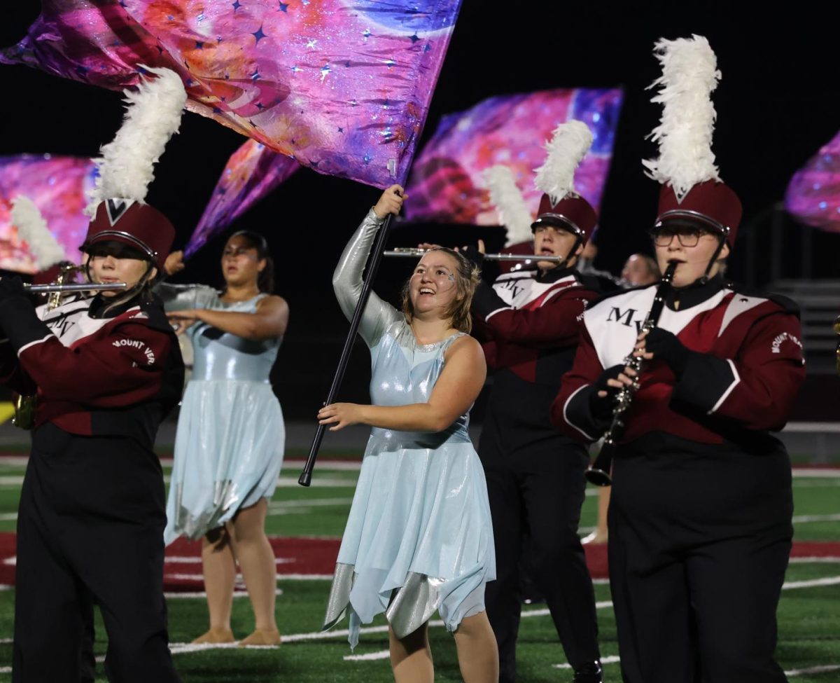 Junior Mae Krapfl flies her colors during the marching band's last show on Oct. 28.