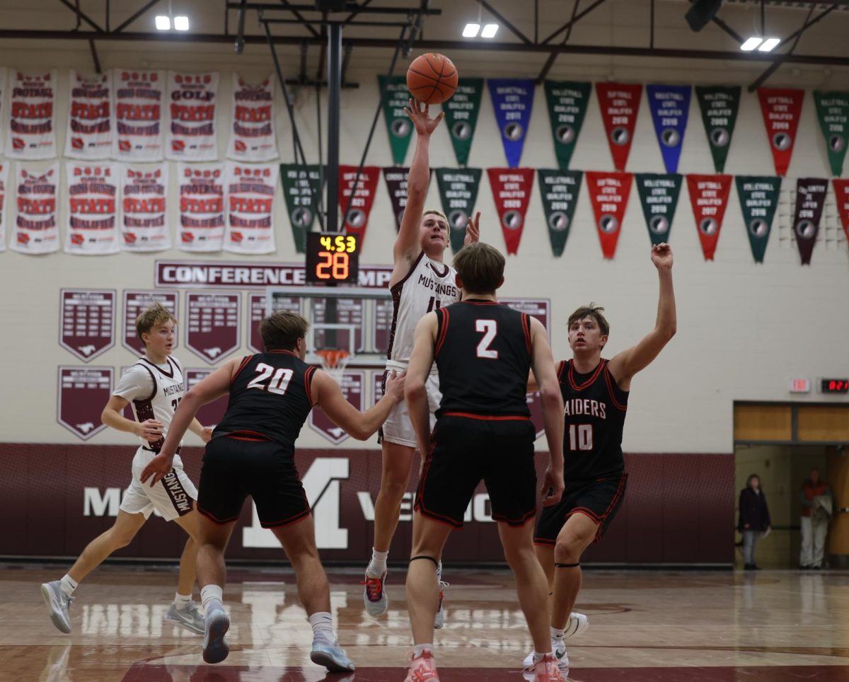 Junior Kellen Haverback (11) jumps to shoot the basketball over his opponents Dec. 13.