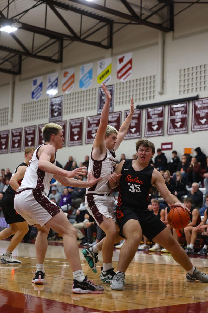 Junior Brogan Meyer (13) braces senior AJ McDermott (12) as he blocks his Solon opponent Dec. 17.